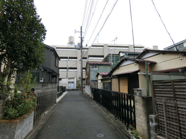 小倉第６マンション外観共用部11｜小倉第６マンションは近隣の周回道路の奥にあります。道路の入り口から概観を見た様子です。周辺は静かな低層住宅地にあります。
