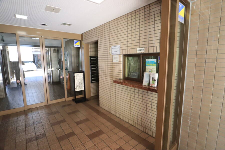 コスモ向島共用部1｜エントランスの床はタイル張りで、落ち着いた色合いのモザイクパターンが施されています。