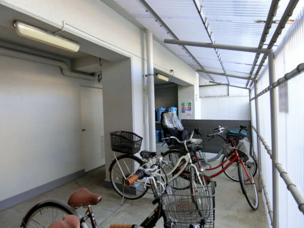 ルシール南大塚外観共用部4｜自転車置き場はエントランスの右手、駐車スペースの向こうに目隠しを設置した状態です。