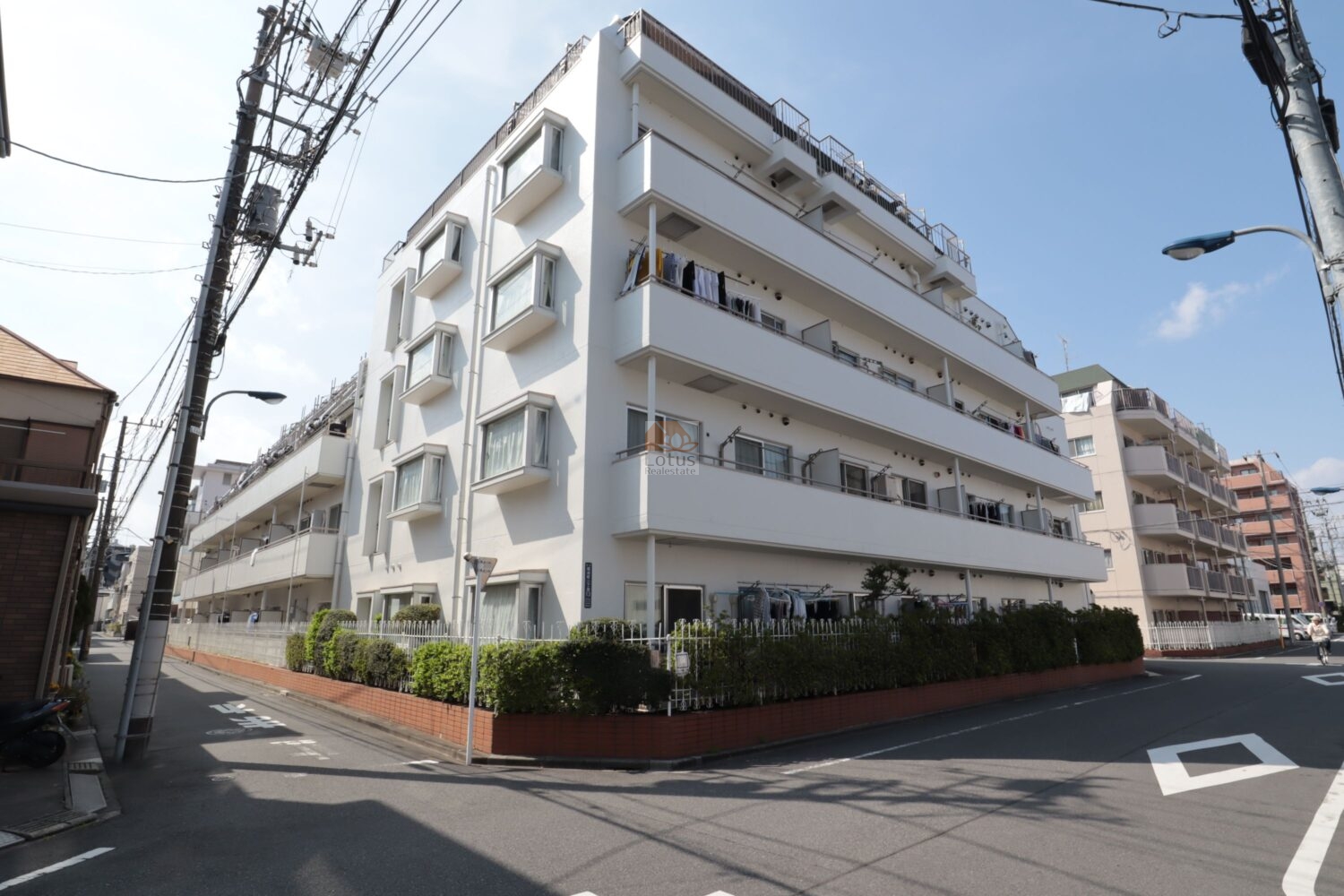 白い外壁が明るく、角地に建つ姿が印象的です。低層の街並みに溶け込みながらも、どの住戸にも光が届く穏やかな環境を感じます。