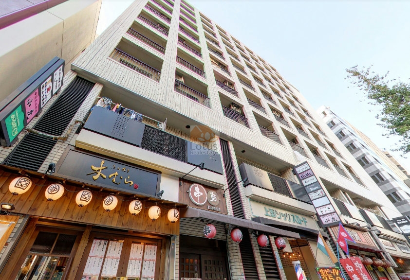 商業ビルが並ぶ上野六丁目の一角に建つ姿。低層部には飲食店が並び、街の灯りが建物の表情を温かく照らします。御徒町駅徒歩2分の利便性を感じる、活気ある通りの景観です。