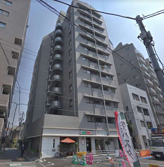 不忍通りに面した角位置で、縦に伸びる外観と1階テナントの庇が連続し、街路と建物の距離感がつかめます。バルコニーの水平ラインと外付け階段の曲線が重なり、都市型の表情として落ち着いて見えます。