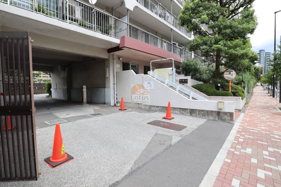 東陽町スカイハイツ共用部1｜建物下部に設けられたピロティ形式の駐車場です。敷地内には誘導表示や植栽が整備され、利便性と安心感を兼ね備えています。