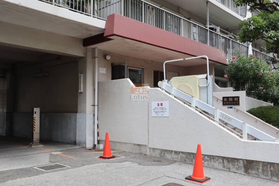 東陽町スカイハイツ共用部3｜建物入口前の階段横には、昇降機付きスロープが設けられ、バリアフリー対応が施されています。外構の植栽も整備され、来訪者にも好印象を与える設計です。