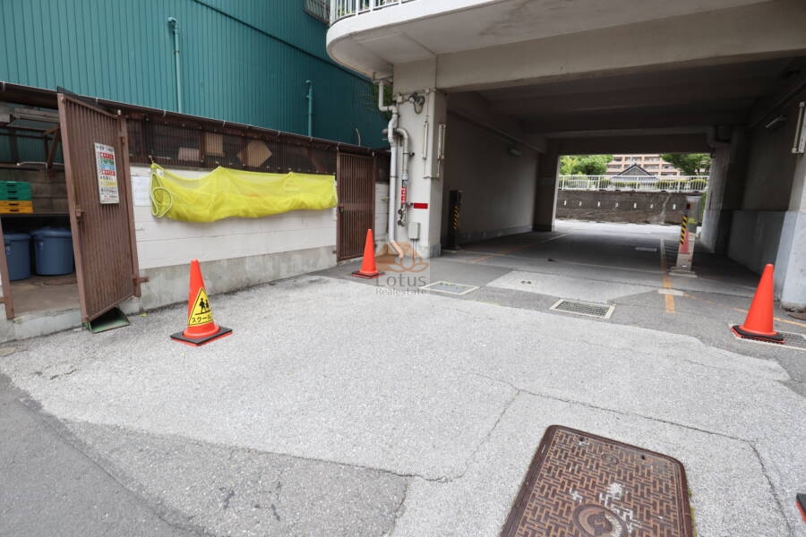 東陽町スカイハイツ共用部2｜駐車場に隣接するゴミ置き場はフェンスで囲われ、分別用のネットや表示板が完備されています。共用部の整理整頓が行き届いており、管理体制の良さが伺えます。