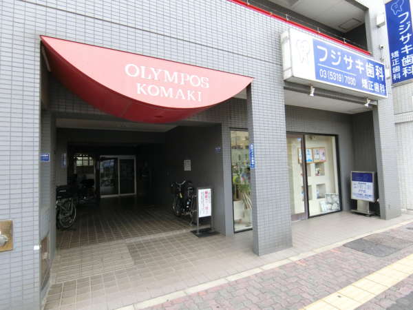オリンポスコマキ外観共用部 (3)｜エントランスの様子です。１階部分は店舗となっています。エントランスアプローチが自転車置き場を兼ねています。