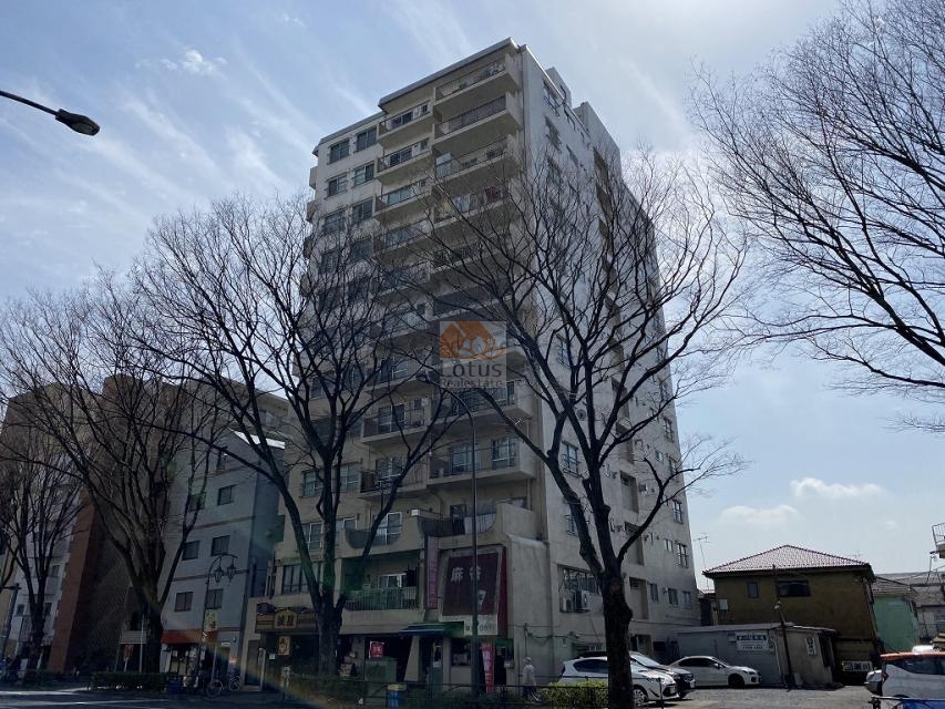 エントピア五月園の外観（甲州街道側）。12階建のスリムなSRC造マンションが、街路樹の並ぶ甲州街道沿いにそびえる。周辺の開けた空間により、高層階からの採光・眺望にも期待ができる構造。エントピア五月園は昭和45年築、12階建てのマンションです。
