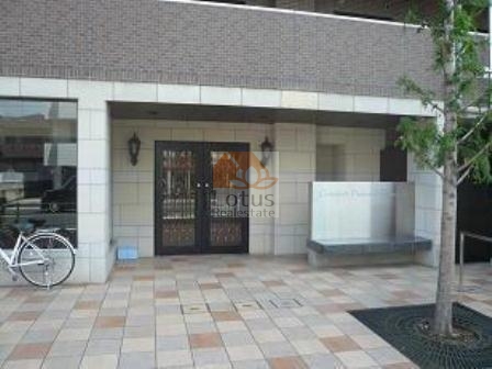 コンフォート・パレス六町エントランス｜エントランスは、周りにはタイルが敷かれ、正面には2つの大きなガラスドアがあり、その両脇にはおしゃれなランプが取り付けられています。