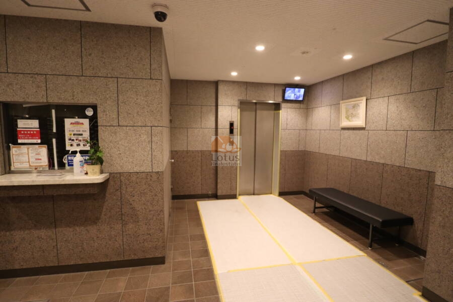 日本橋箱崎ハイツ共用部2｜共用ロビーとエレベーターホール。ベンチが設けられ、待機やちょっとした休憩にも便利です。防犯カメラとモニター付きで、安心感のある共用スペースです