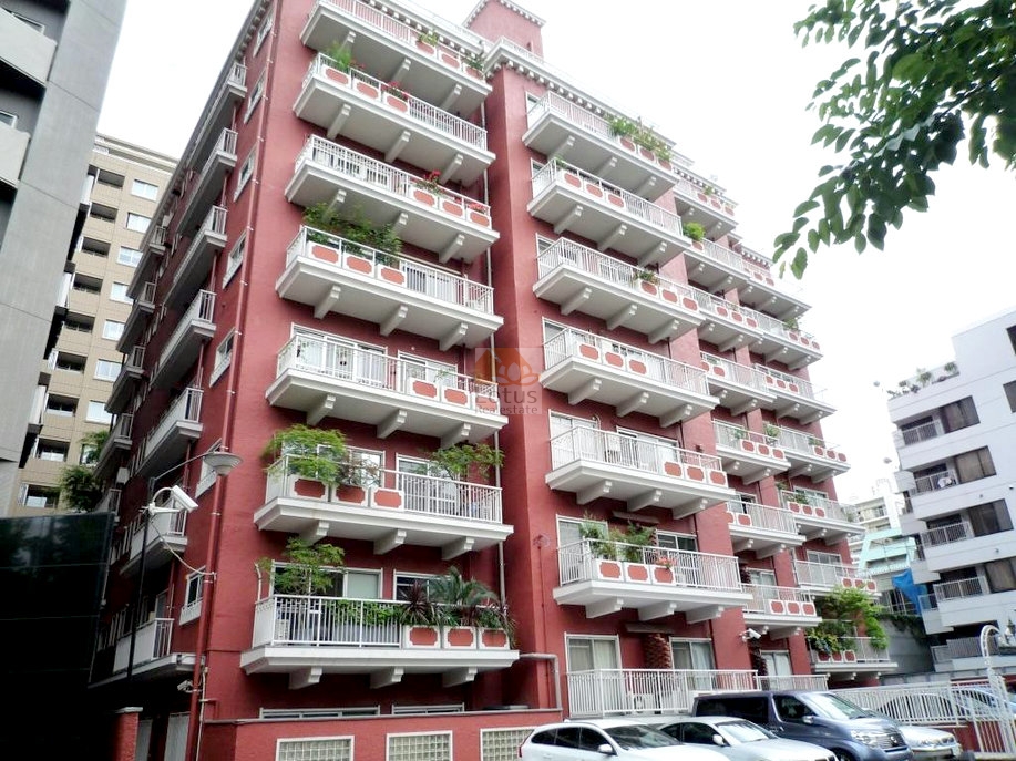 赤茶色の外壁を持つ11階建ての集合住宅で、各住戸に白い手すり付きのバルコニーがあり、複数のバルコニーには植栽が置かれており、建物全体に緑のアクセントが加わっています。NK麹町コータースは、昭和44年築、11階建てのマンションです。