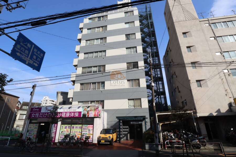 タック曳舟外観3｜タック曳舟の外観はシンプルでモダンなデザインで、グレーと白の配色が目を引きます。マンションの1階部分には、フィットネスクラブが入っています。