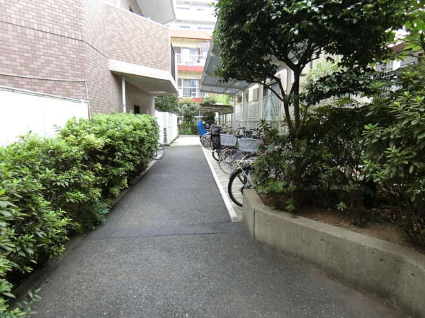 ライオンズマンション五反野駅前通り外観共用部1｜建物に向かってエントランスのすぐ右も駐輪場でしたが、こちらは駐輪場の車路の途中に建物内ゴミスペースなどの通路と兼用していました。