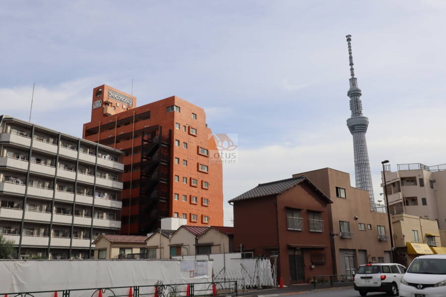 ライオンズマンション言問外観3｜スカイツリーを背景に、古い町並みも混在する都市の風景です。建物の多様性が東京の住宅事情を反映している地域性です。