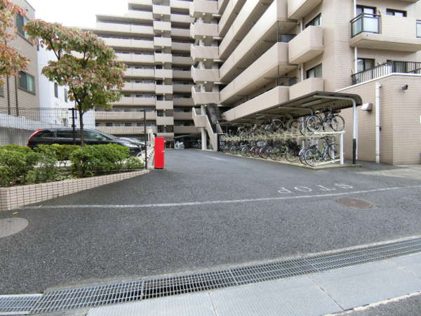 ライオンズガーデン錦糸町外観共用部6｜駐車場・駐輪場の様子です。2段ラック式の駐輪場を備え、台数を確保。奥行きのある敷地で車と自転車をしっかり収容しています。