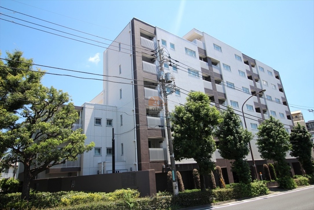 千歳船橋駅徒歩8分の環八通りに佇む中層レジデンスです。白とブラウンのタイルを組み合わせた外壁が、直線的で理性的な印象を与えます。環八通り沿いながらも、歩道の緑と建物前の植栽がクッションのように街の音を和らげ、穏やかな街並みを演出しています。ペット飼育可で、帰宅時に見上げる建物の整ったラインが日々の安心感を象徴しているように感じます。グランスイート世田谷桜丘は、平成22年築、7階建てのマンションです。