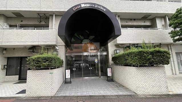 ライオンズマンション練馬 (3)｜エントランスは、黒いアーチ屋根が目を引くデザインで、建物の正面に重厚感を与えています。アプローチには階段と手すりが設けられています。