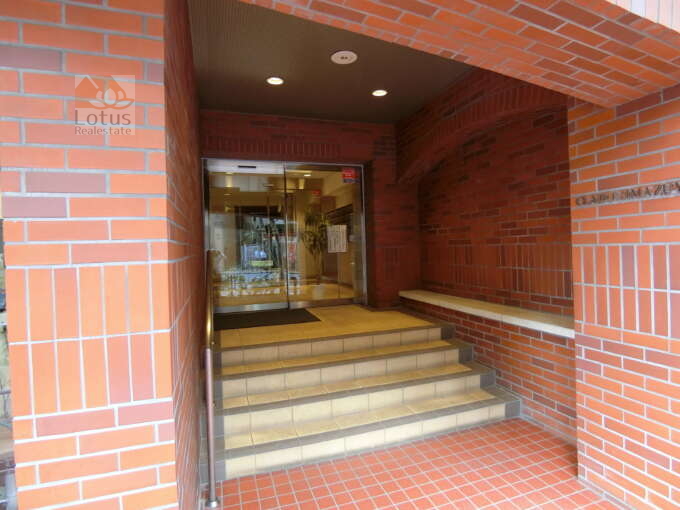 クレール島津山外観共用部2｜エントランスは、赤レンガ調の壁に囲まれており、温かみを感じさせます。エントランスに入るための数段の階段があり、手すりも設置されているため、安全です。