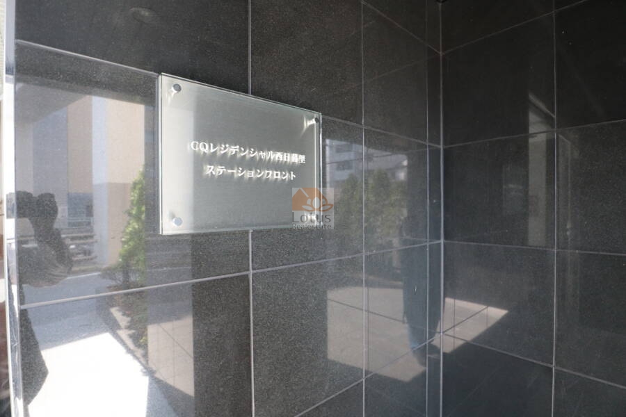 ＣＱレジデンシャル西日暮里ステーションフロントエントランス3｜CQレジデンシャル西日暮里ステーションの館銘板。黒いタイル壁に設置されたガラス製プレートに、マンション名が白文字で表示されています。建物の正確な名称を確認できるカットです。