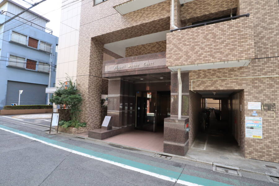 日暮里サニーコートエントランス1｜外壁はベージュ系のタイル張りですが、エントランスはパープル系の大理石でシックです。