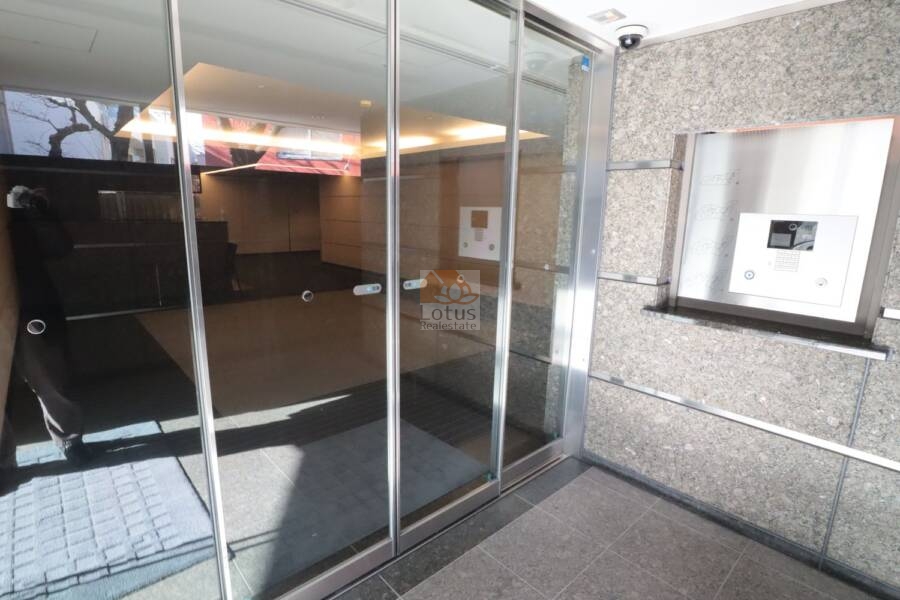 グランブルー鷺ノ宮共用部2｜エントランスのガラス扉の向こうには、ホテルライクな照明のロビー空間が見えています。タイルと石材の組み合わせが品の良さを感じさせ、訪れるたびに背筋が伸びる気がします。
