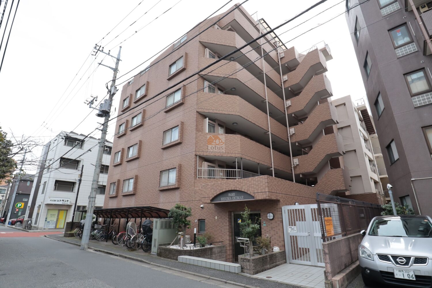 街角を曲がった瞬間に、タイル貼りの外観がすぐ目に入ってきて安心感があります。駅前らしい生活の音がほどよく流れていて、建物の段差のないエントランスが日常の動線を穏やかに整えていると感じています。自転車置場が軒下にまとまり、雨をしのぎながら利用できる点が暮らしやすさに結びついているといえます。