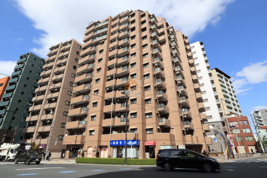 モリス日暮里駅前は、日暮里駅前交差点角に建つ14階建ての外観で、ブラウン系の外壁、歩道沿いの1階にはテナント看板が並びます。モリス日暮里駅前は、平成9年築、14階建てのマンションです。