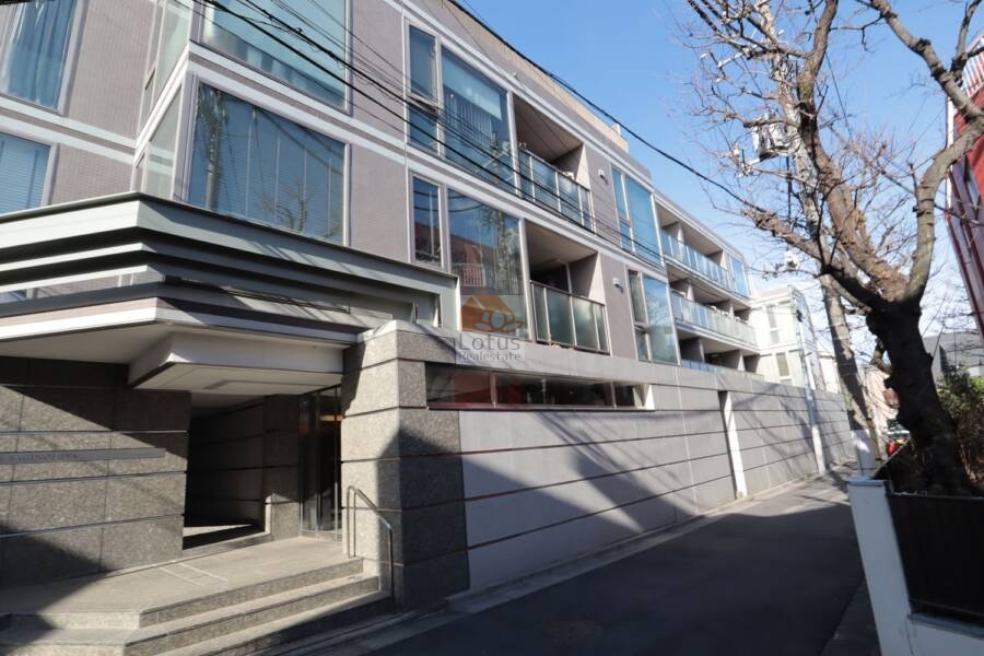 グランブルー鷺ノ宮外観3｜道路のカーブに沿うように設計された建物外観は、敷地形状を巧みに活かした構成。植栽と塀が街並みに穏やかに溶け込んでおり、居住者のプライバシーも確保されています。