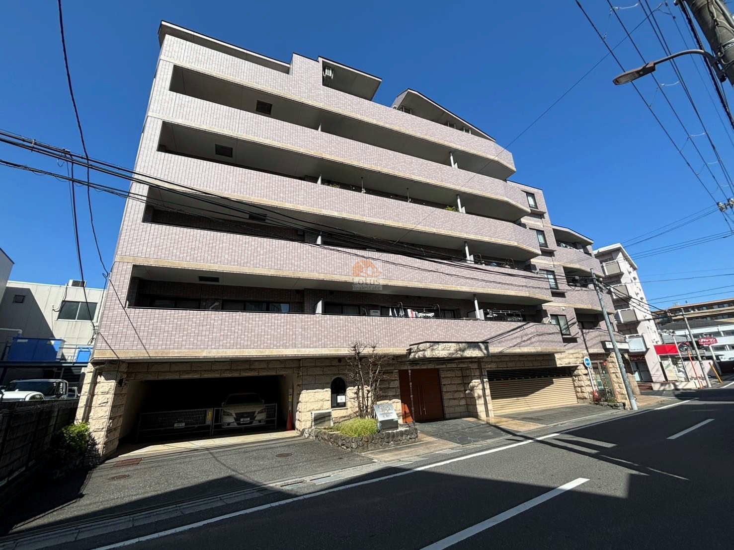 タイル貼りの外壁が整い、通り沿いにバルコニーが水平にのびています。1階はシャッター付きの車路が見え、街区との距離感がつかめます。ウイングストリーム氷川台コートは、平成12年築、66階建てのマンションです。