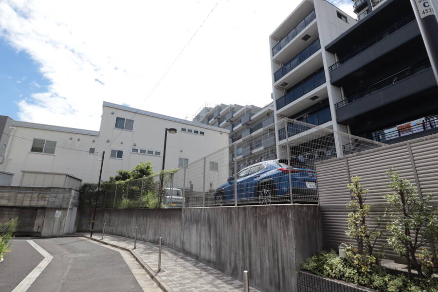 レーベン北千住エアクロスタワー外観6｜建物東側の駐車場スペース。区画ごとにフェンスで囲まれており、防犯や安全性への配慮が感じられます。植栽もほどよく整えられています。
