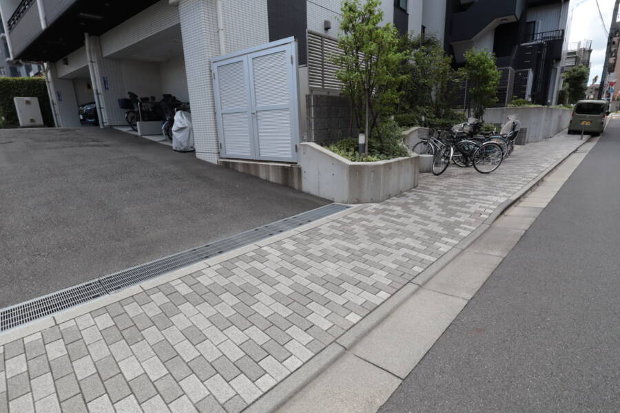 レーベン北千住エアクロスタワー共用部4｜マンション前面の舗装歩道と駐輪スペース。ゆったりとした道幅で、自転車やベビーカーの利用にも配慮された整備状況が伺えます。