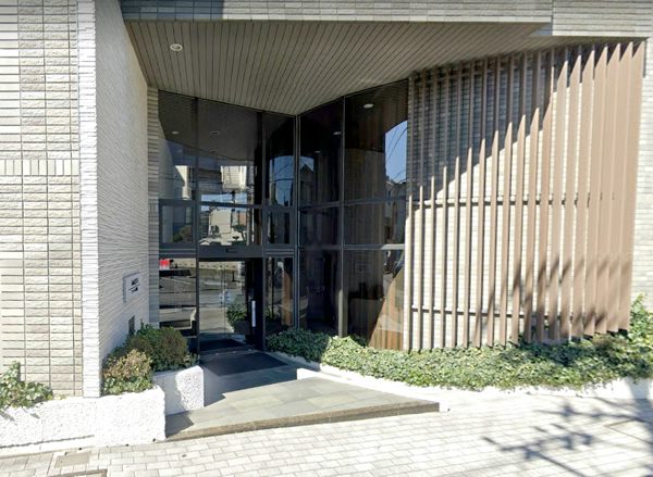 スマータス不動前エントランス１｜垂直の木製ルーバーがあり、建物にモダンで上品な雰囲気を加えています。床は滑りにくいタイルが使用されており、安全に配慮されています。