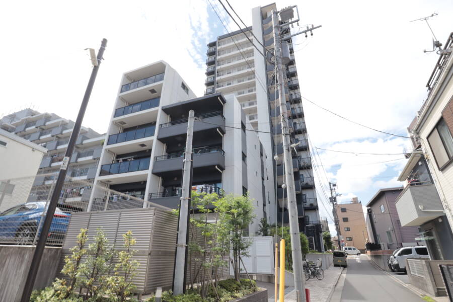 レーベン北千住エアクロスタワー外観5｜建物東側の通りから見た様子です。縦に伸びるスリムなタワー型と、低層階のバルコニーがバランスよく配置され、都心ならではの密集地にゆとりを感じさせます。