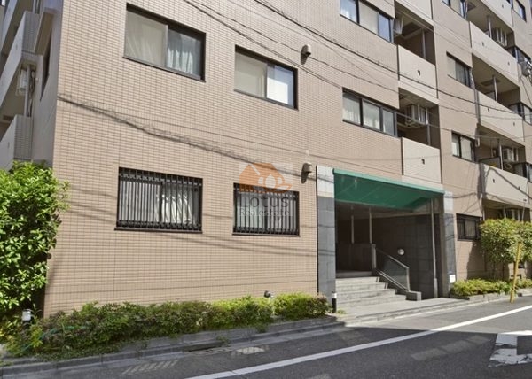 マイキャッスル水天宮前壱番館外観３｜マイキャッスル水天宮前壱番館の正面ファサード。緑色の大きな庇とエントランス階段があり、両側には整えられた植栽が並んでいます。