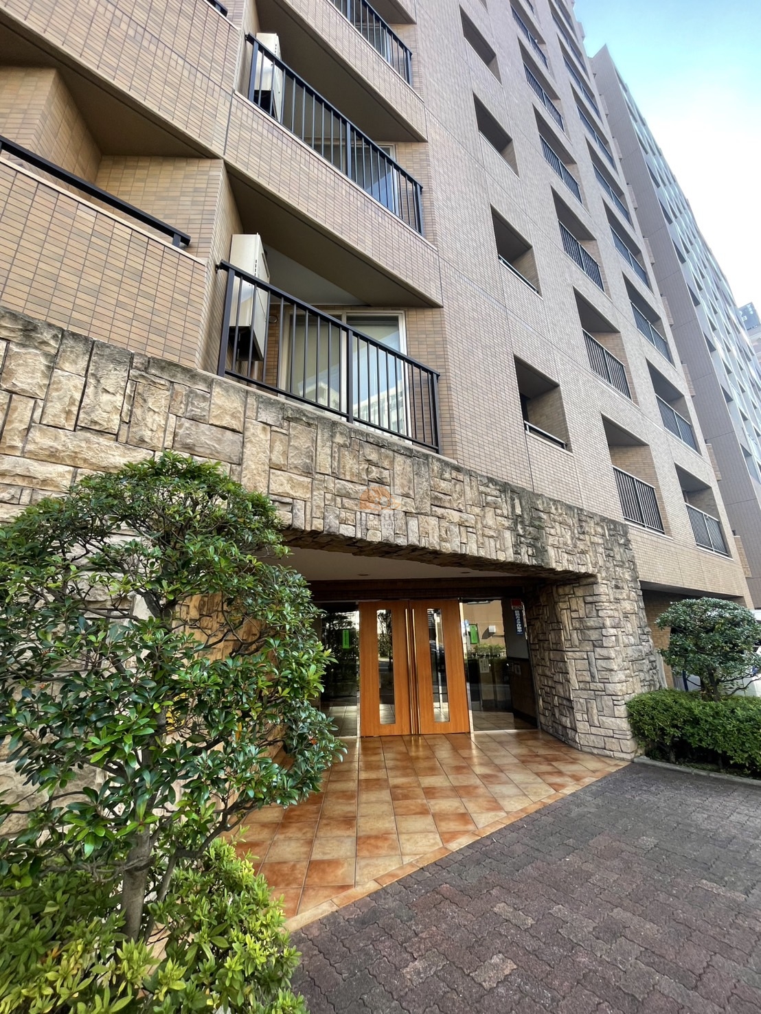 タイル張りの外観にバルコニーのラインが整い、下町の街並みに対して意外とすっきりした印象です。建物全体のボリューム感はありますが、圧迫感は控えめで、空を見上げたときの抜けも感じられます。駅徒歩4分という立地を考えると、日常動線に寄り添った外観構成といえます。