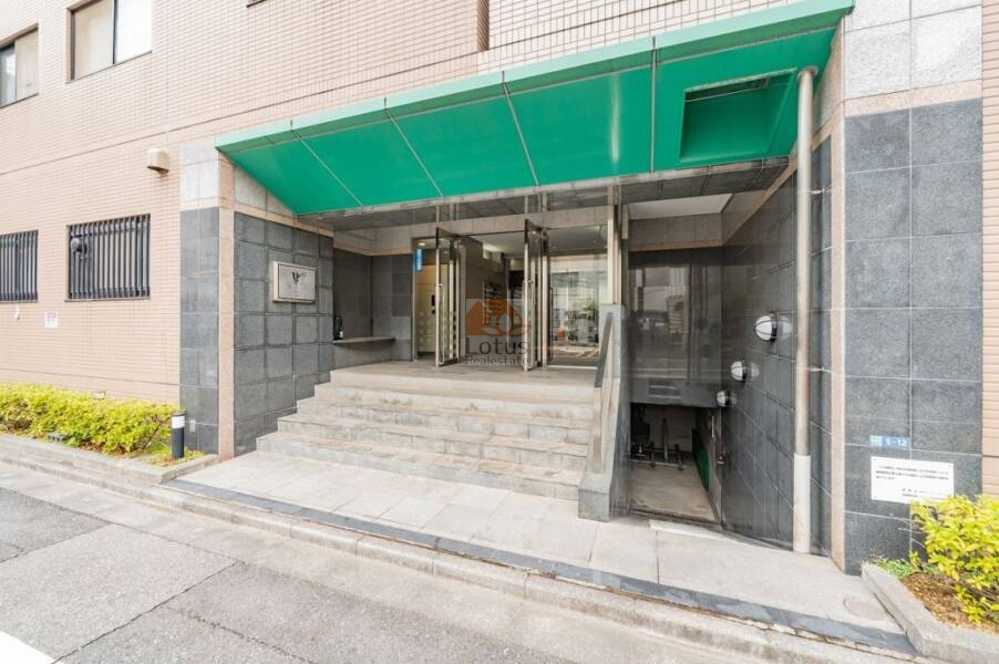 マイキャッスル水天宮前壱番館エントランス１｜マイキャッスル水天宮前壱番館のエントランス部分。段差のある階段と庇付きのガラスドア、スロープが整備され、地下階への入口も確認できます。