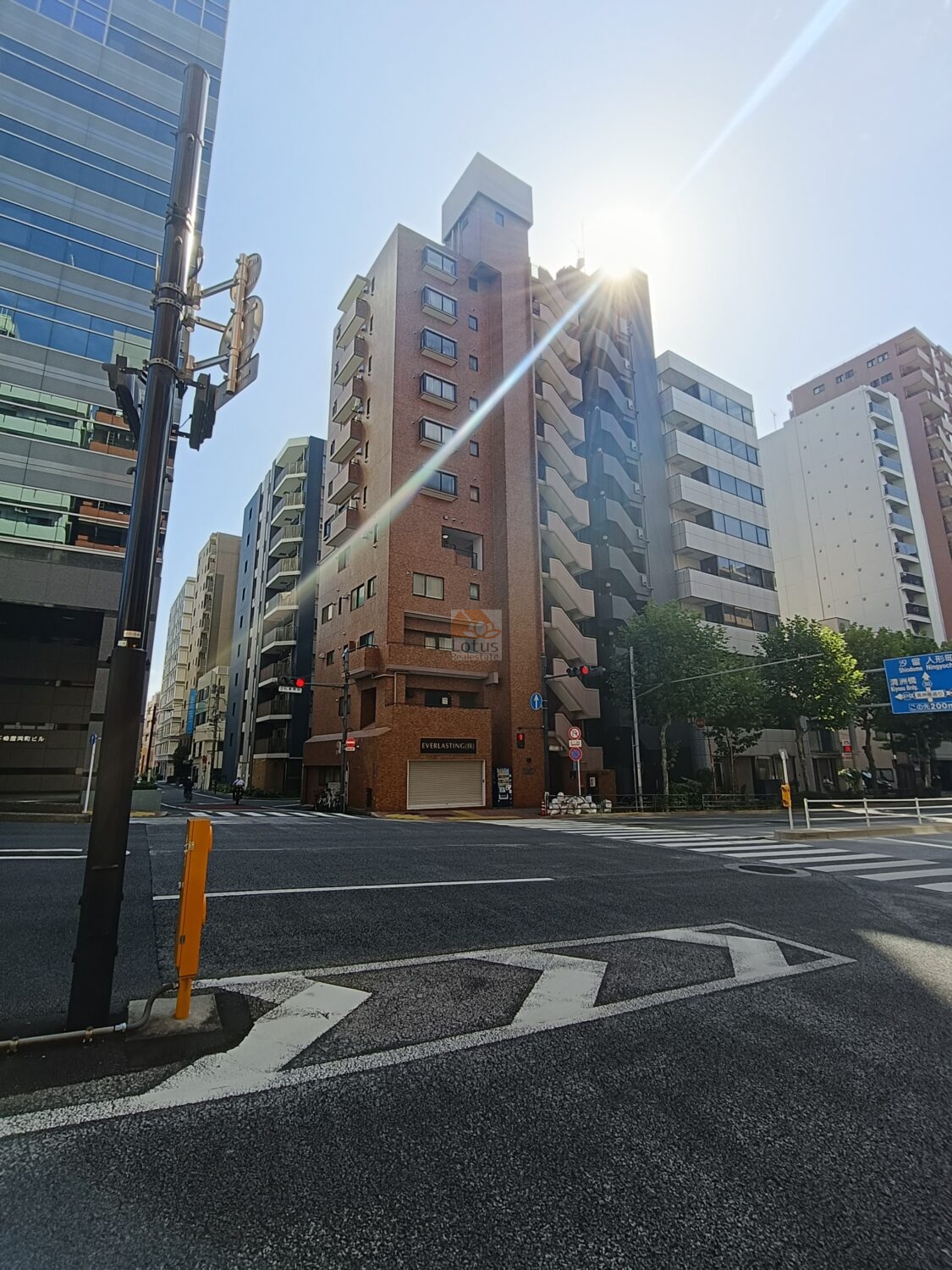 光建ハイムブリリアンス日本橋浜町弐番館の外観です。煉瓦調タイルの外壁が穏やかな陽射しを受け、都心の風景に温かみを添えています。新大橋通りの交差点に面し、ビジネス街の中で静かに存在感を放っています。