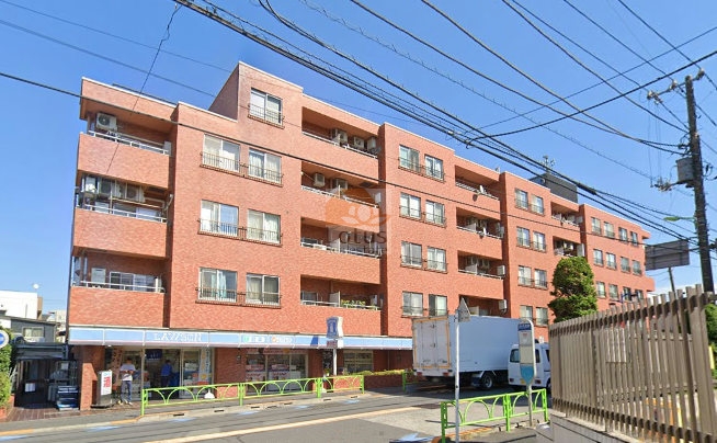 シャンボール弦巻の南西側外観。レンガ調タイル貼りの5階建てで、1階部分にはコンビニ店舗が入り、通り沿いに面している。バルコニー付き住戸が並び、開放感のある住環境を演出。シャンボール弦巻は、昭和52年築、5階建てのマンションです。