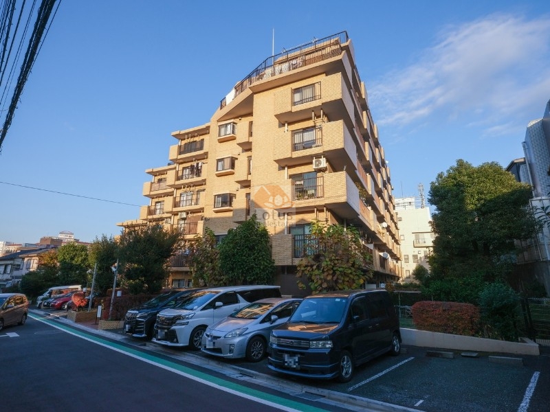 ライオンズマンション赤羽第２の南西側外観。ベージュ系タイル貼りの外壁が穏やかな街並みに調和し、植栽も丁寧に整えられています。7階建の中層構造で、低層住宅が多いエリアの中で存在感のある建物です。ライオンズマンション赤羽第２は昭和62年築、7階建てのマンションです。