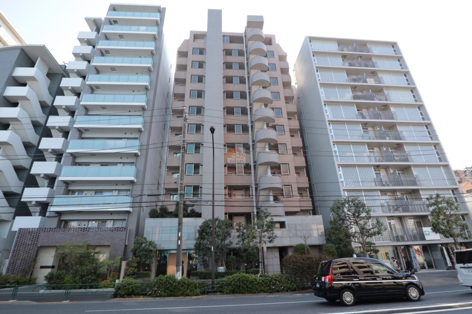 ルイシャトレ尾久の外観です。明治通り沿いに立ち並ぶマンション群の中で、落ち着いたベージュタイルが街並みに自然に溶け込んでいます。前面には植栽が整い、駅近ながらも穏やかな暮らしのリズムを感じます。