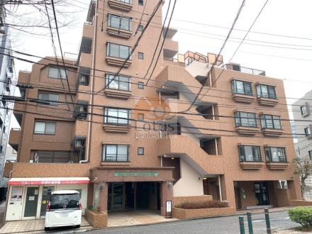 ライオンズマンション小石川第５の建物外観。ブラウン系タイル貼りの落ち着いたファサードが、文京区の街並みに調和しています。前面道路は広く、建物との距離も確保されています。ライオンズマンション小石川第５は、平成3年築、7階建てのマンションです。