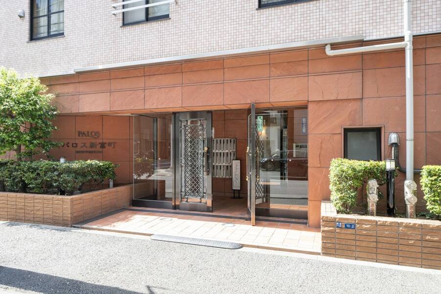 パロス新富町エントランス１｜エントランスの壁は温かみのある赤茶色のタイルで覆われており、建物の落ち着いた雰囲気を感じさせます。