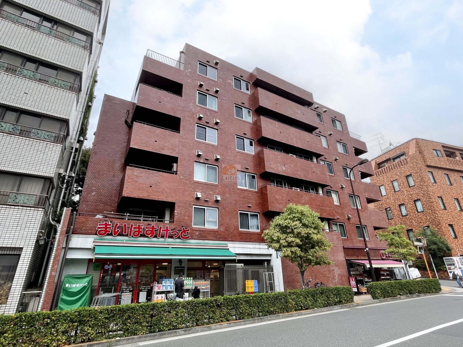 「目黒」駅徒歩5分という都心近接ポジションにありながら、歩道沿いに落ち着いたスケール感で佇むレンガタイル外観です。駅前の喧騒と距離をとりつつ、夜間オートロックで安心して帰宅できる導線が確保されています。建物1階には「まいばすけっと」が入り、日常の買物も便利な住環境。