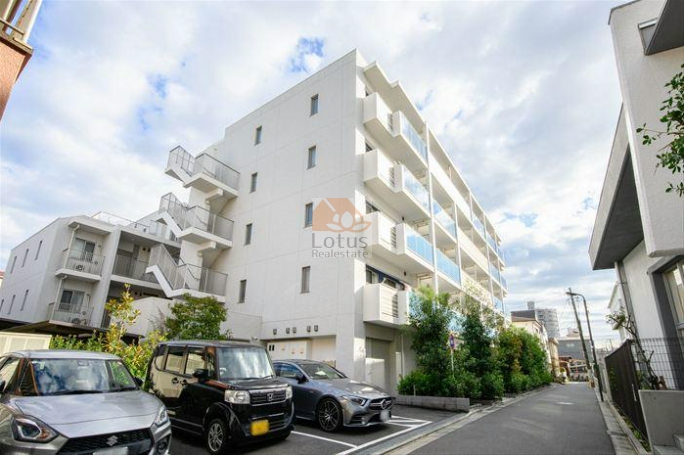 白を基調とした外観に、ガラス手すりのバルコニーが整然と並ぶファサードです。三方道路に囲まれた敷地のため建物との距離が確保され、前面には植栽帯が設けられています。低層5階建というスケール感もあり、車の走行音が抑えられた静かな環境が印象に残ります。