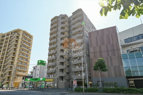 大通りに面して建つ中層マンションの姿が広がります。街の景観と調和しながらも凛とした存在感を放っています。1階部分には店舗が入居しており、建物利用の多様さを物語ります。隣接する現代的な外観の建物との対比も印象的で、生活の舞台が都市の中にしっかりと溶け込んでいることを感じさせてくれます。アミスタ北糀谷は、平成10年築、12階建てのマンションです。