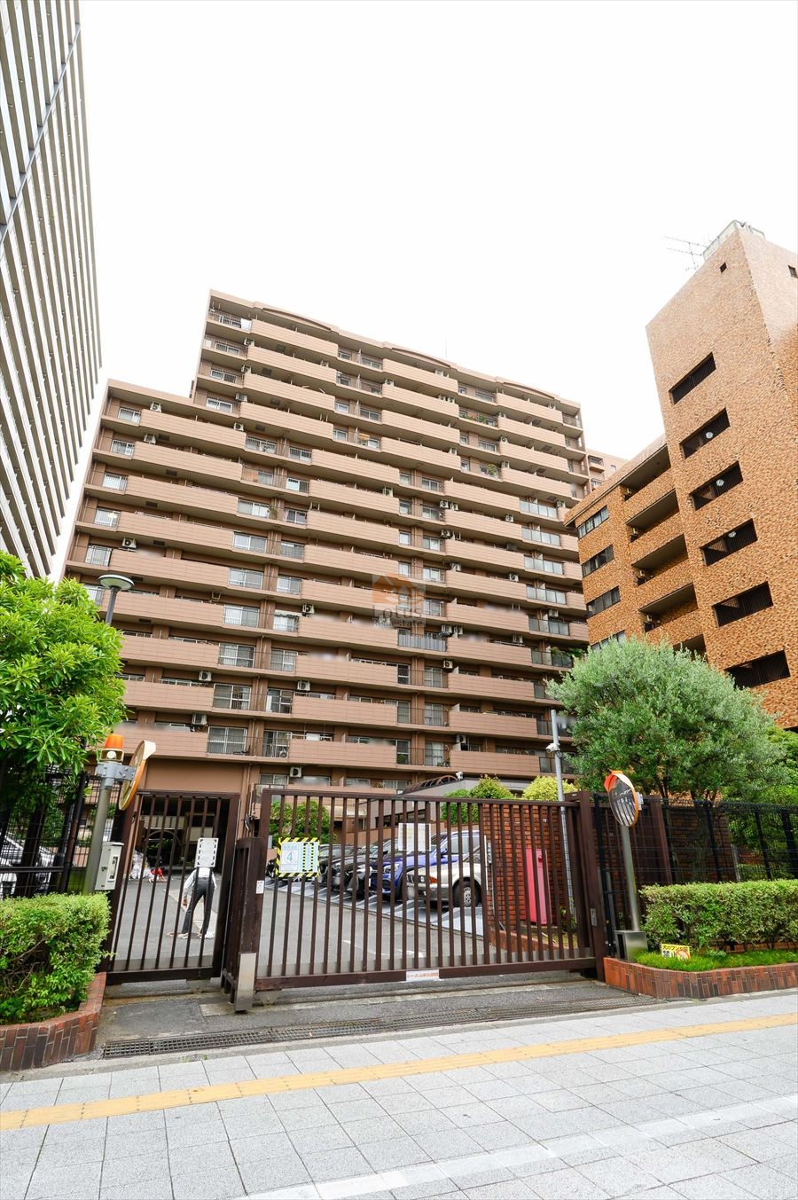 大森海岸パークハウスは、昭和59年築、15階建てのマンションです。前面には駐車場と門扉付きのセキュリティゲートが設置され、都市型マンションとしての安心感を演出。豊かな植栽が敷地を囲み、温かみのある茶系タイルの外壁が街並みに調和。総戸数294戸のスケール感と、落ち着いた景観が共存する大規模レジデンス。