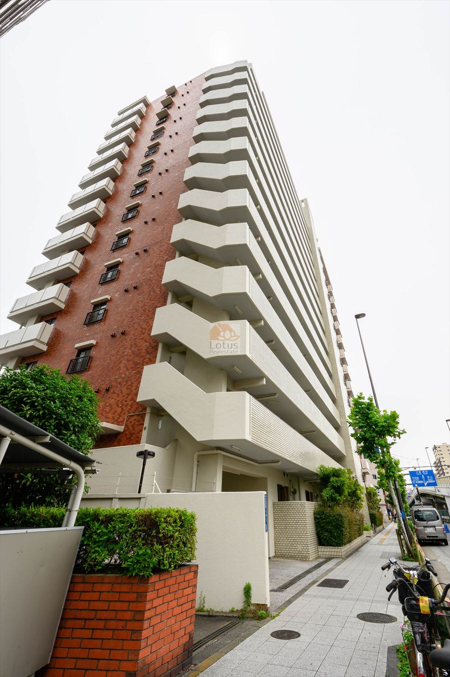 大森本町ハイツは、昭和57年築、14階建のスケール感が際立つ立ち上がりと、白系タイルとレンガ調のツートンカラーが特徴的なファサード。歩道沿いの緑と整備された前面道路が、駅近物件の利便性を引き立てます。