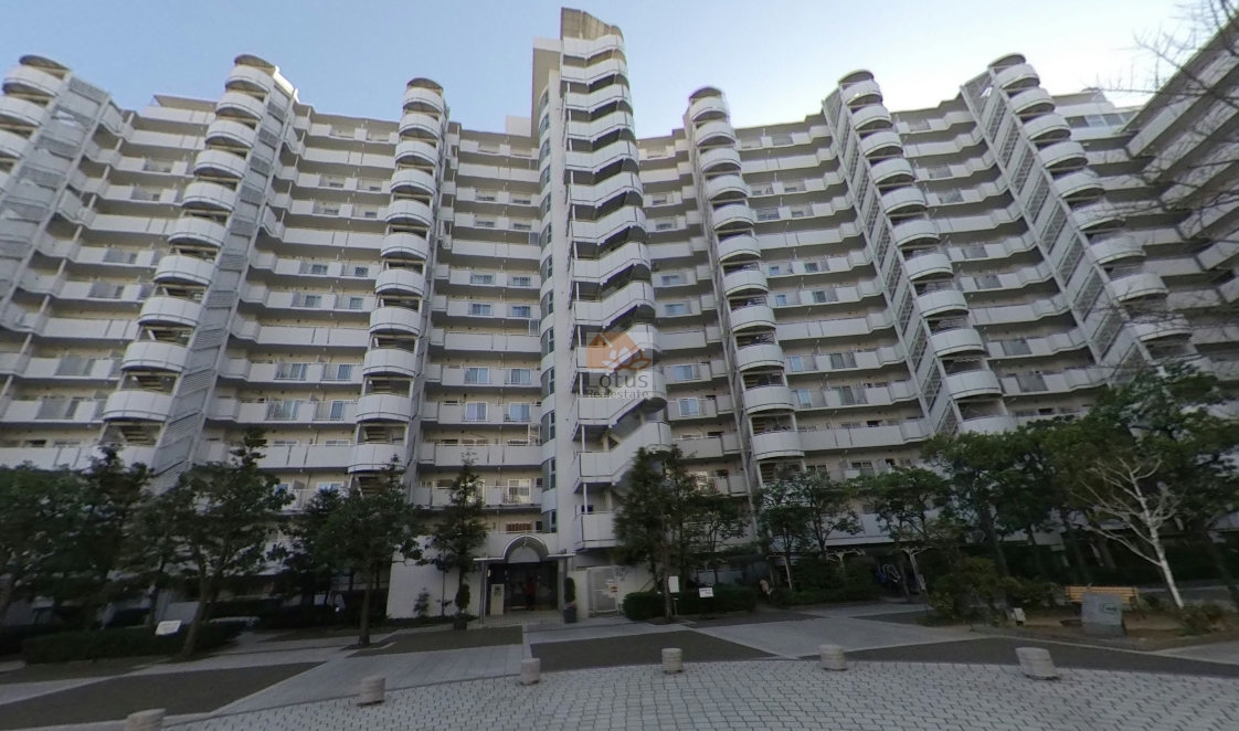 東急ドエルアルス多摩川のメインエントランス前の外観。整然と並んだ白基調のファサードが、総戸数461戸のスケール感と安心感を感じさせます。中央の直線的な階段棟が、住棟全体の立体感と統一感を演出しています。東急ドエルアルス多摩川は、昭和62年築、14階建てのマンションです。