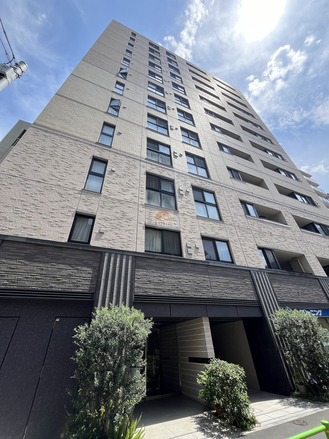 外観は12階建の縦に伸びるフォルムが印象的です。ベージュ系のタイルと濃い色の基壇部が切り替わっていて、町並みに自然に溶け込む落ち着いた質感です。周辺は築地駅徒歩5分の都心エリアですが、ゆとりある歩道と植栽の緑が視界に入ってきて、住宅としての安心感が感じられます。オープンレジデンシア銀座築地は、平成30年築、12階建てのマンションです。