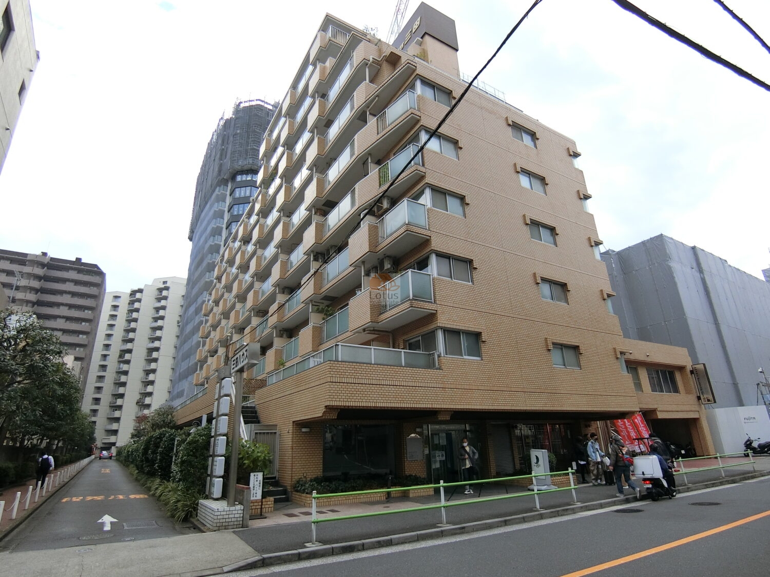 カーサ三田の建物外観（正面・西側）。地上10階建てのSRC造で、ベージュ系タイル貼りの外壁が特徴。通りに面した区画で店舗併設の利便性も兼ね備える。カーサ三田は、昭和60年築、10階建てのマンションです。