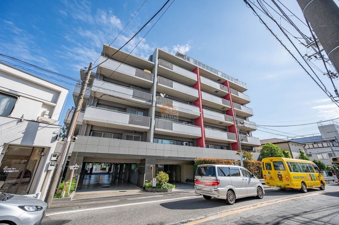 穏やかな住宅街の中に佇む建物で、グレーの外壁に赤い縦ラインがアクセントになっています。バルコニーのガラス手すりが軽やかで、街並みに開放感を与えています。クレッセント千歳船橋インテイストは、平成15年築、7階建てのマンションです。